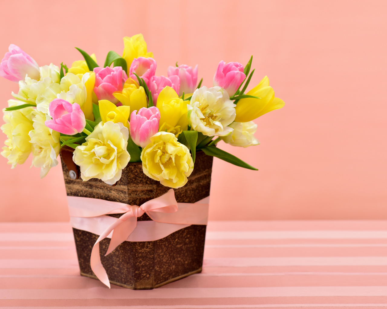 Букет красивых разноцветных тюльпанов в вазе на розовом фоне