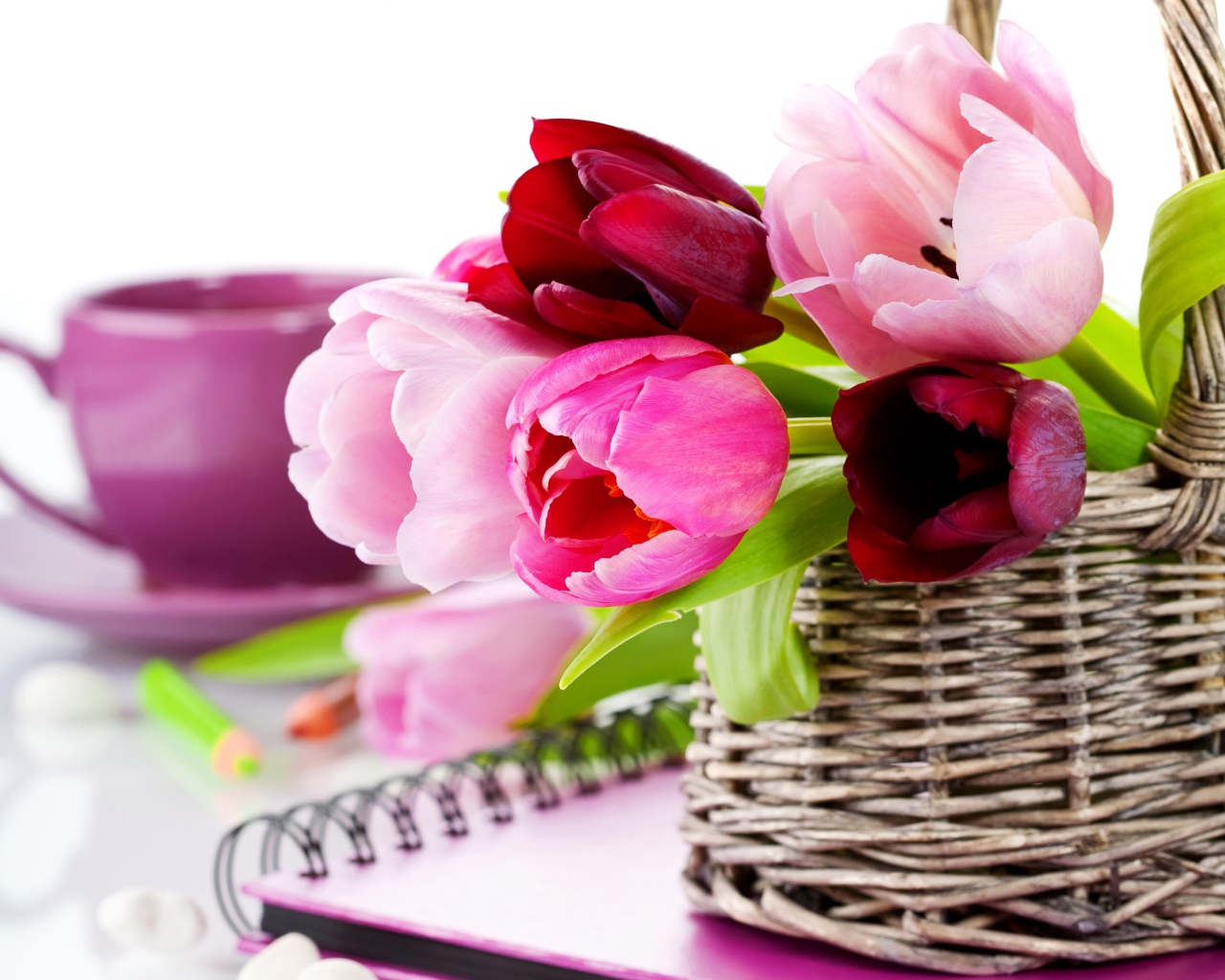 Букет разноцветных тюльпанов в корзине на столе с блокнотом