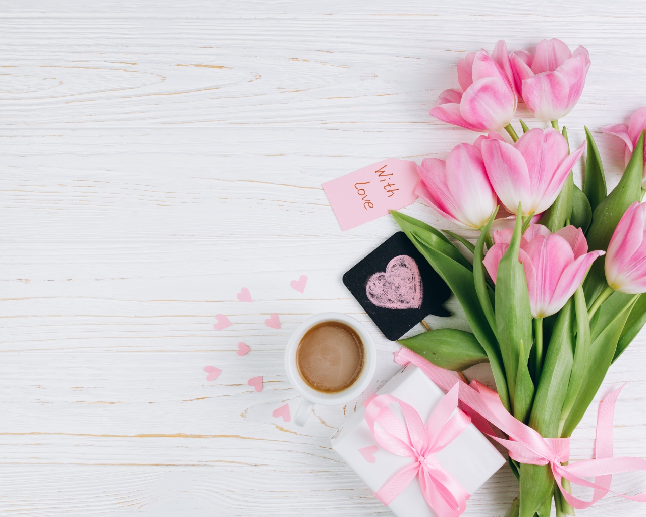 Букет розовых тюльпанов на столе с чашкой кофе и подарком 