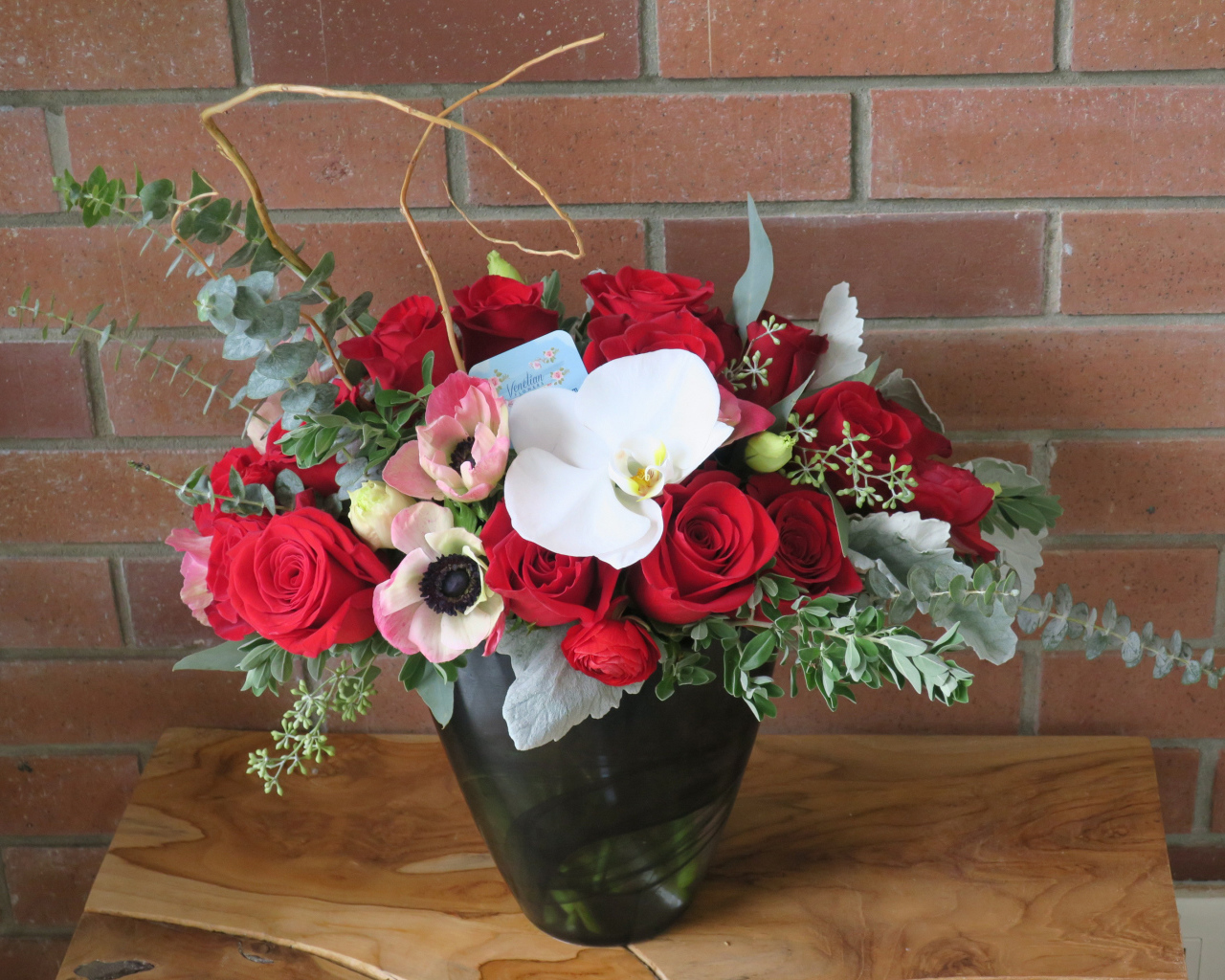 Букет с цветами анемоны, розы и орхидеи у стены 