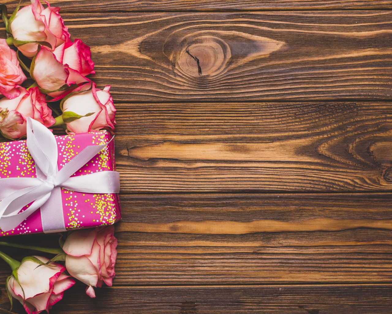 Подарочная коробка с букетом роз на деревянном фоне 