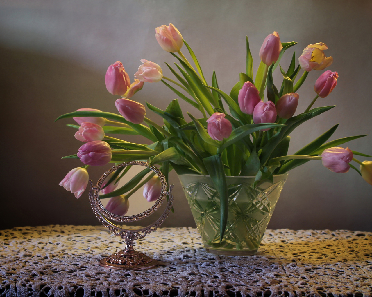 Розовые тюльпаны в стеклянной вазе на столе с зеркалом 