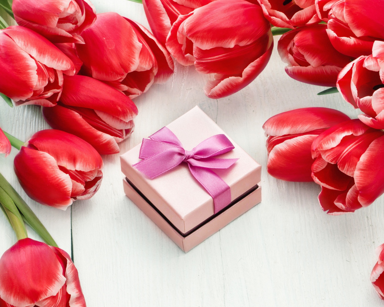 Красные тюльпаны на деревянной поверхности с подарком
