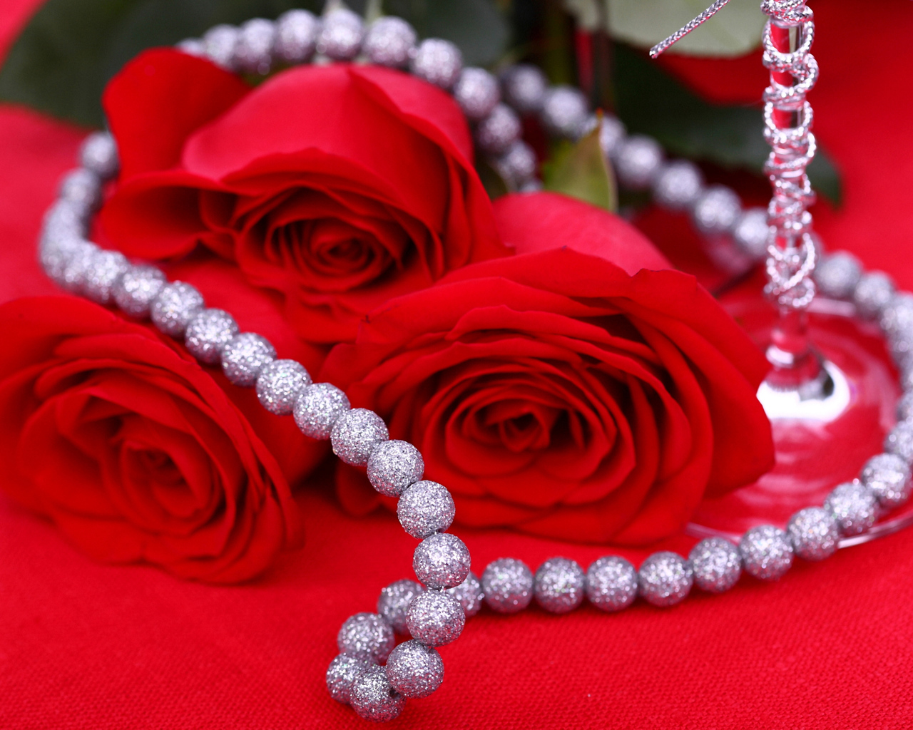 Три красные розы с украшением на красном фоне