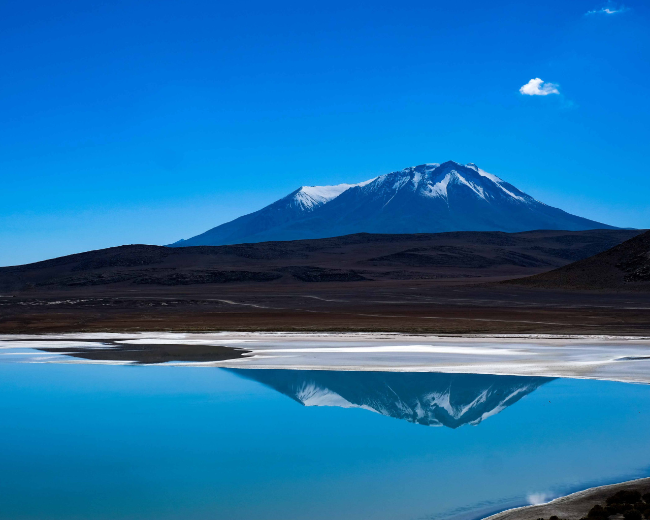 Гора отражается в воде на фоне голубого неба