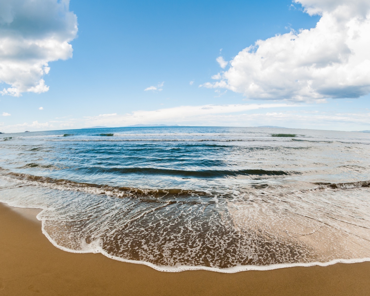 Морская волна на песке под красивым небом с белыми облаками