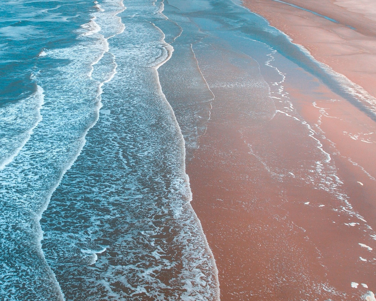 Нежные белые волны омывают песчаный берег океана 