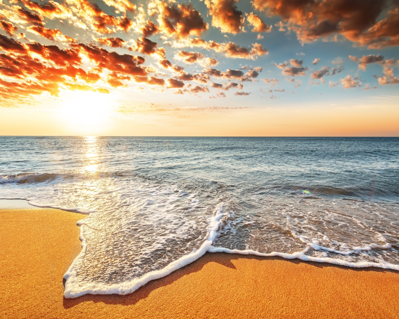 Морская волна омывает песок на берегу под красивым небом