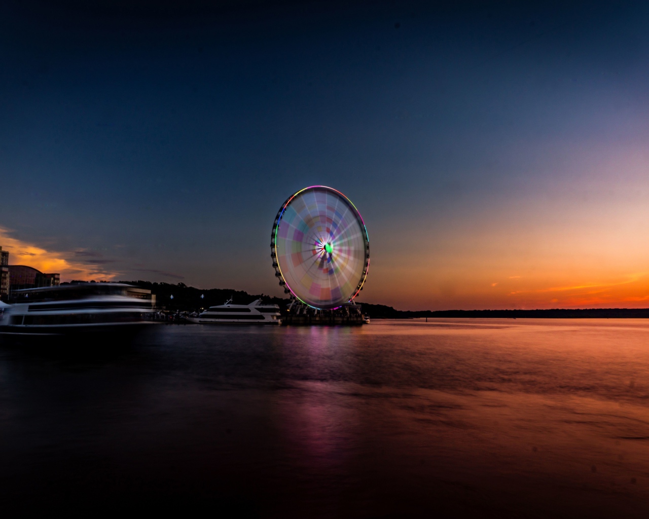 Колесо обозрения у воды на закате