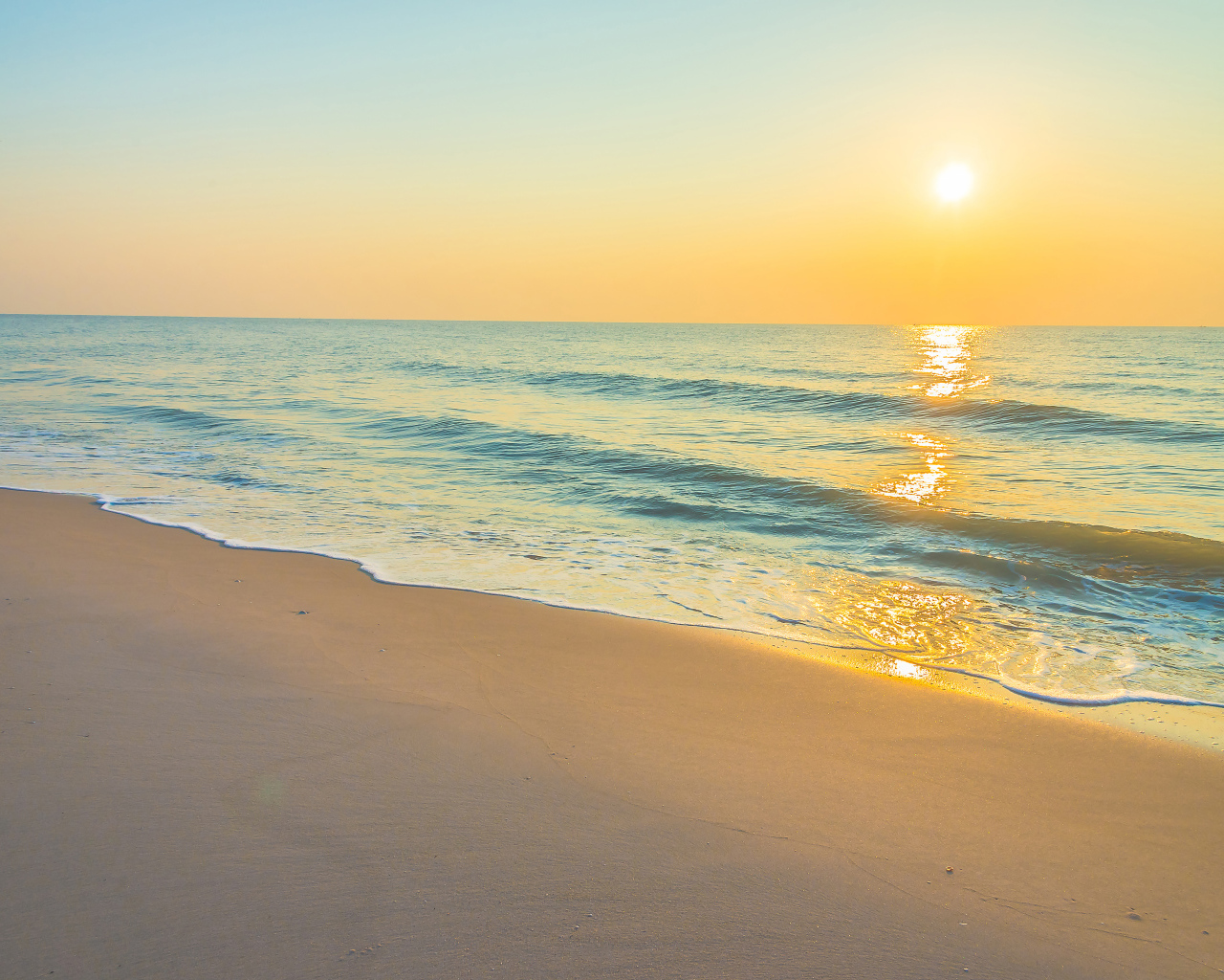 Морские волны на желтом песке на закате солнца летом