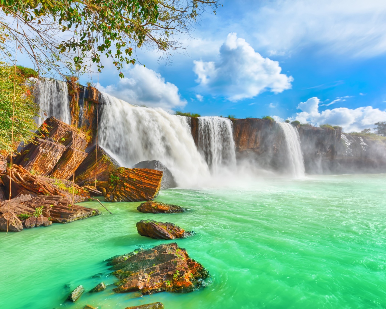 Быстрый водопад стекает со скалы под красивым голубым небом