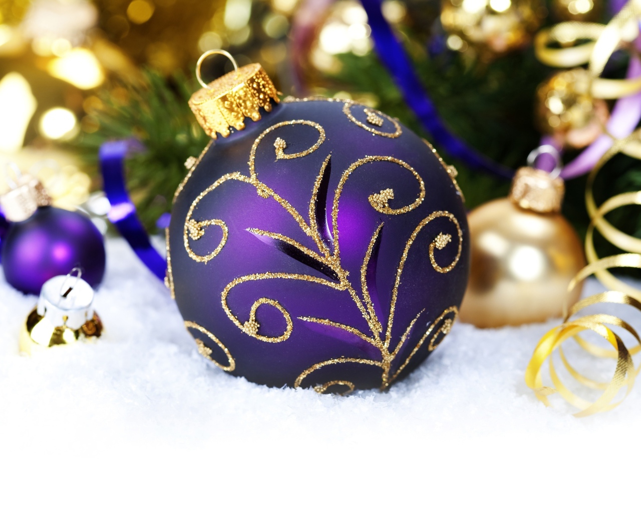 Красивая фиолетовая елочная игрушка лежит на снегу