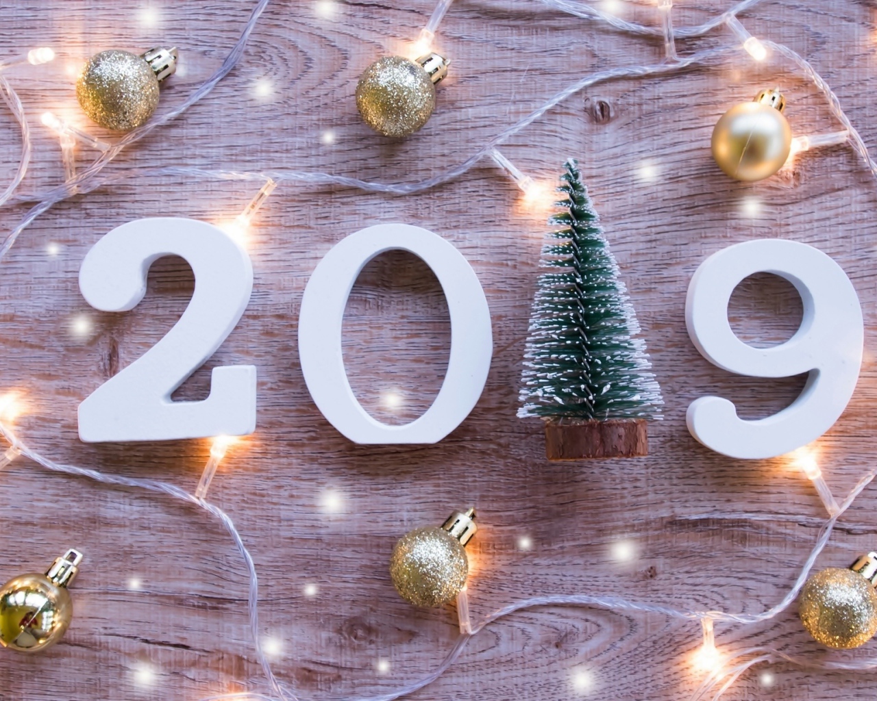 Цифры 2019 на деревянном фоне с елочными игрушками и гирляндой