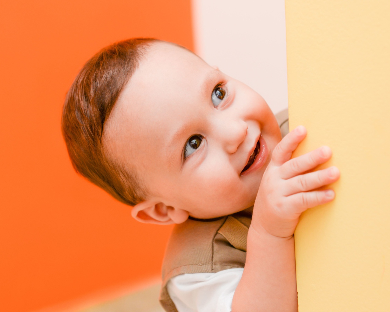 Маленький любопытный мальчик выглядывает из-за стены