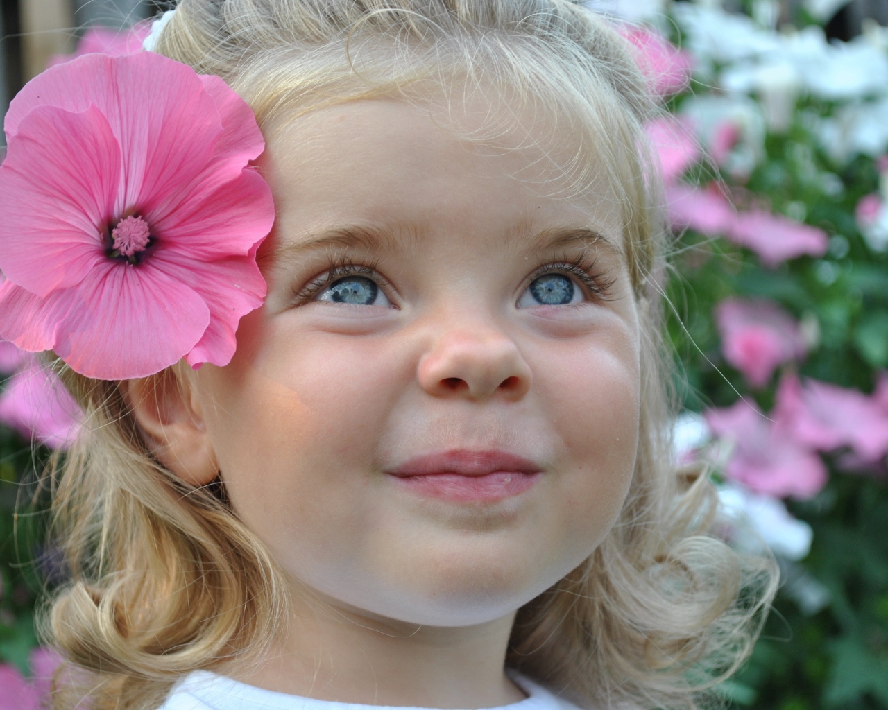 Милая маленькая девочка блондинка с цветком в волосах
