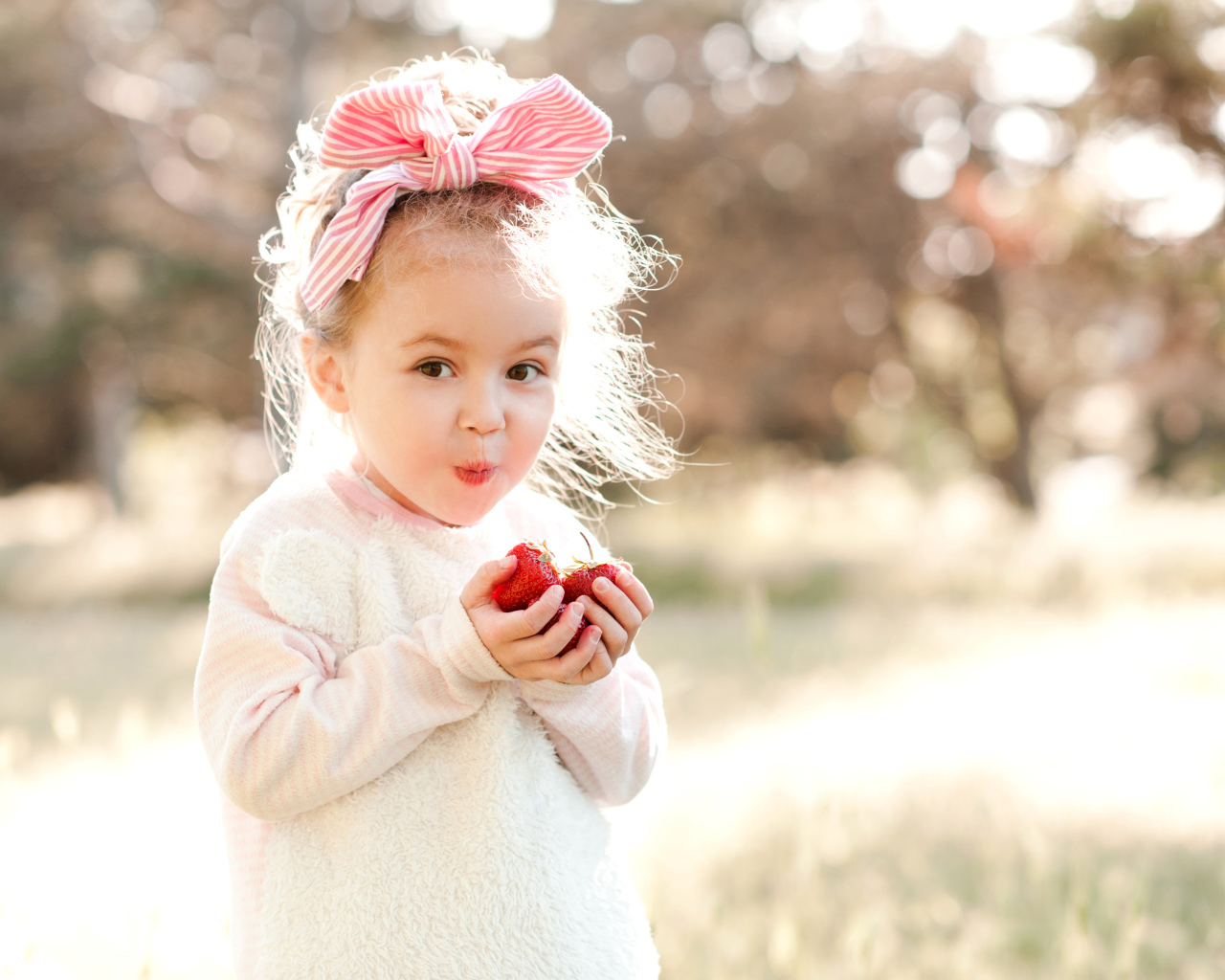 Милая маленькая девочка ест клубнику