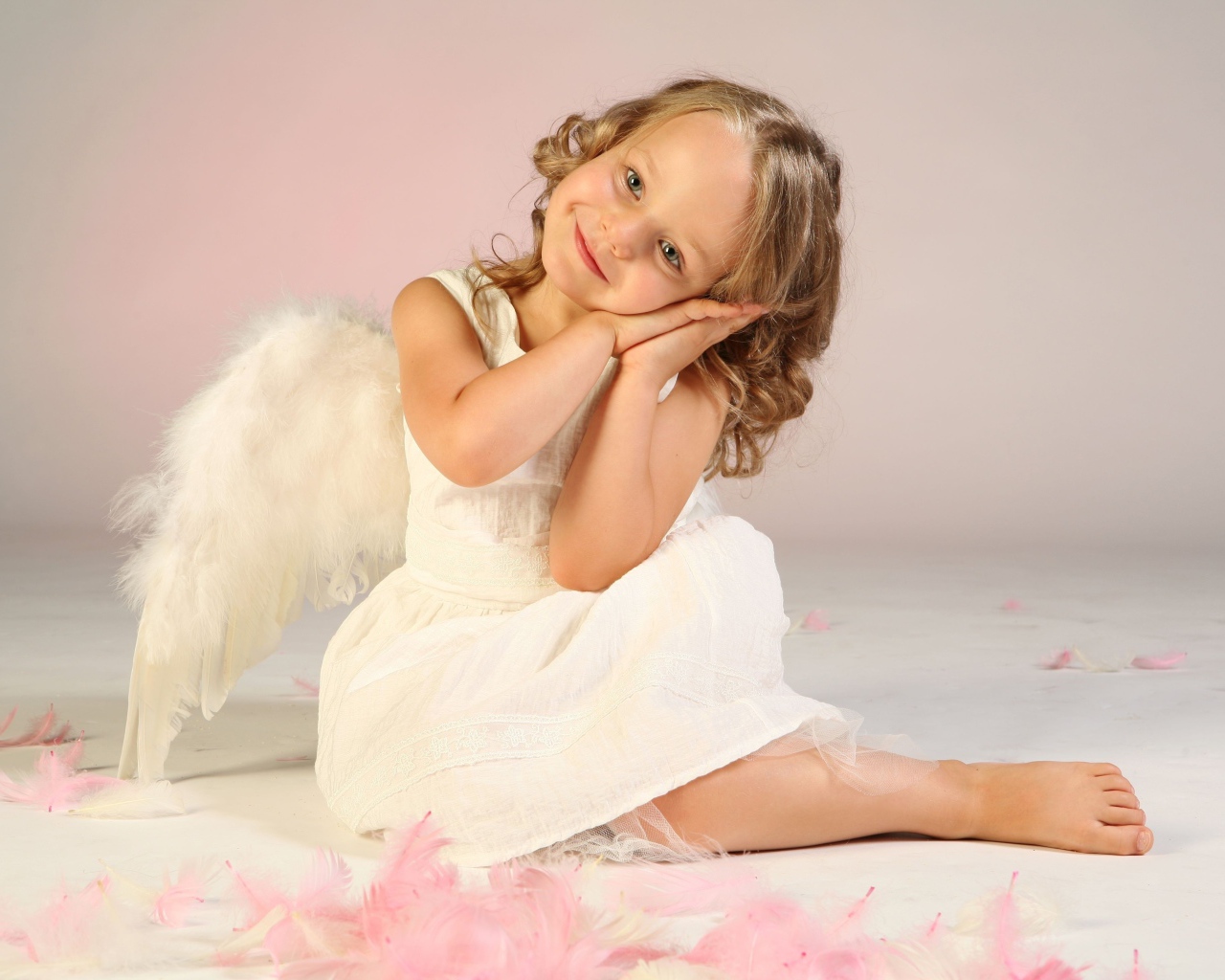 Милая маленькая девочка в белом платье с крыльями ангела