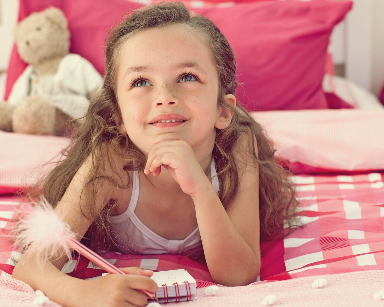 Замечтавшаяся маленькая девочка лежит на кровати