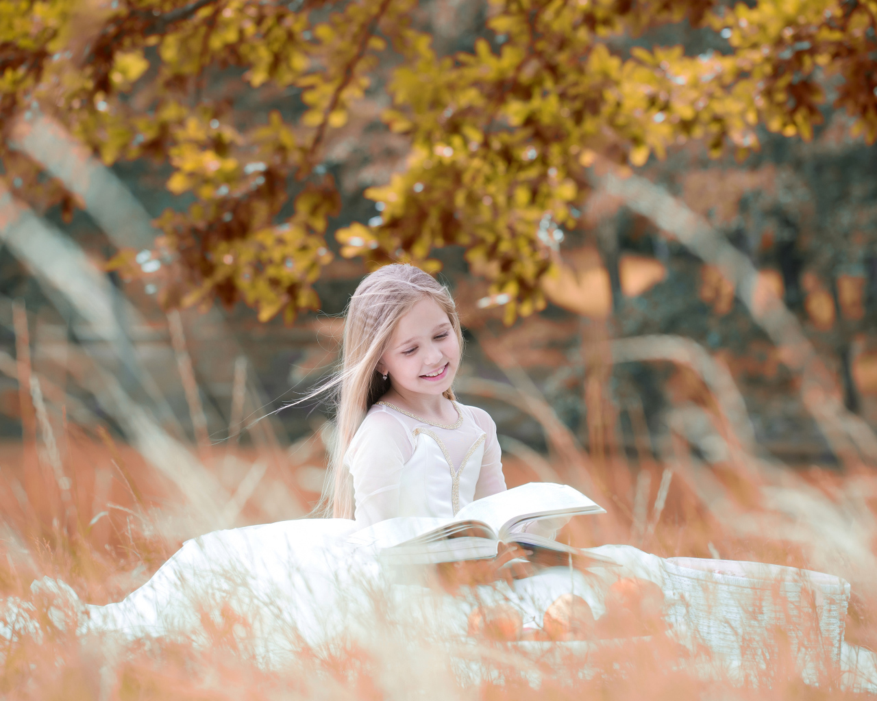 Девочка в красивом белом платье читает книгу на природе