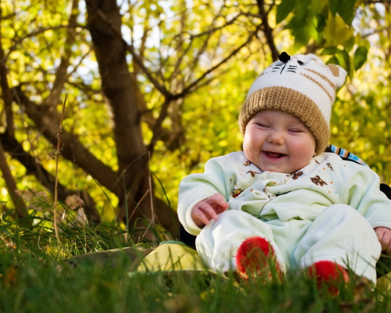 Смеющийся грудной ребенок сидит на траве