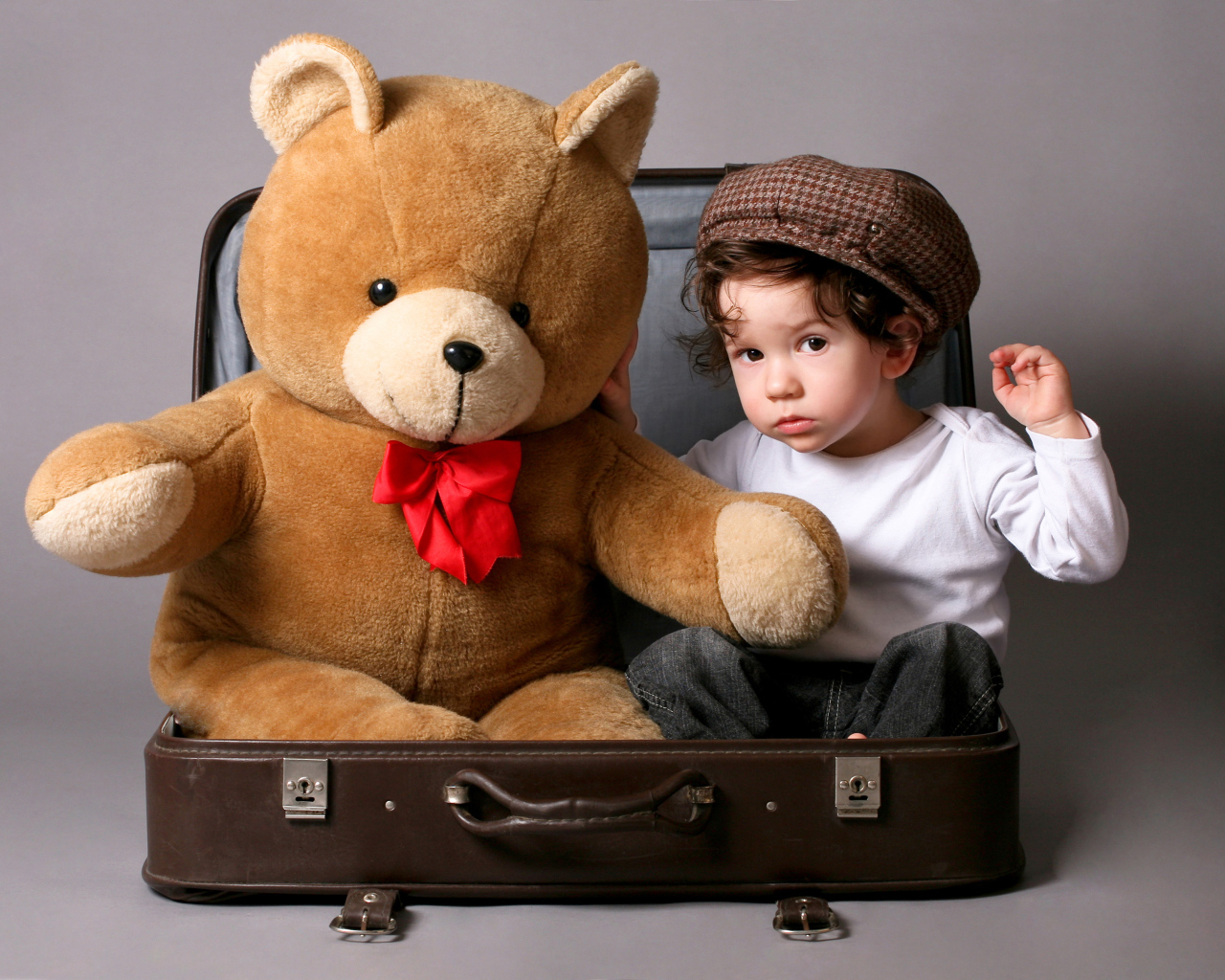 Маленький мальчик сидит в чемодане с плюшевым мишкой 