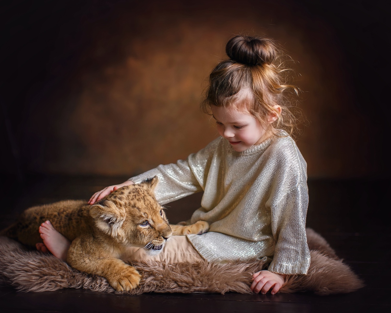 Маленькая девочка гладит маленького львенка