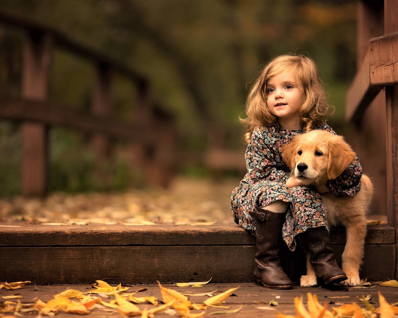 Маленькая девочка с золотистым ретривером сидит на мосту