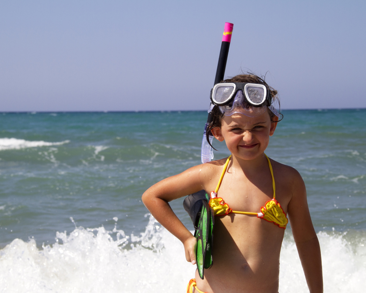 Маленькая девочка в очках и с ластами на море