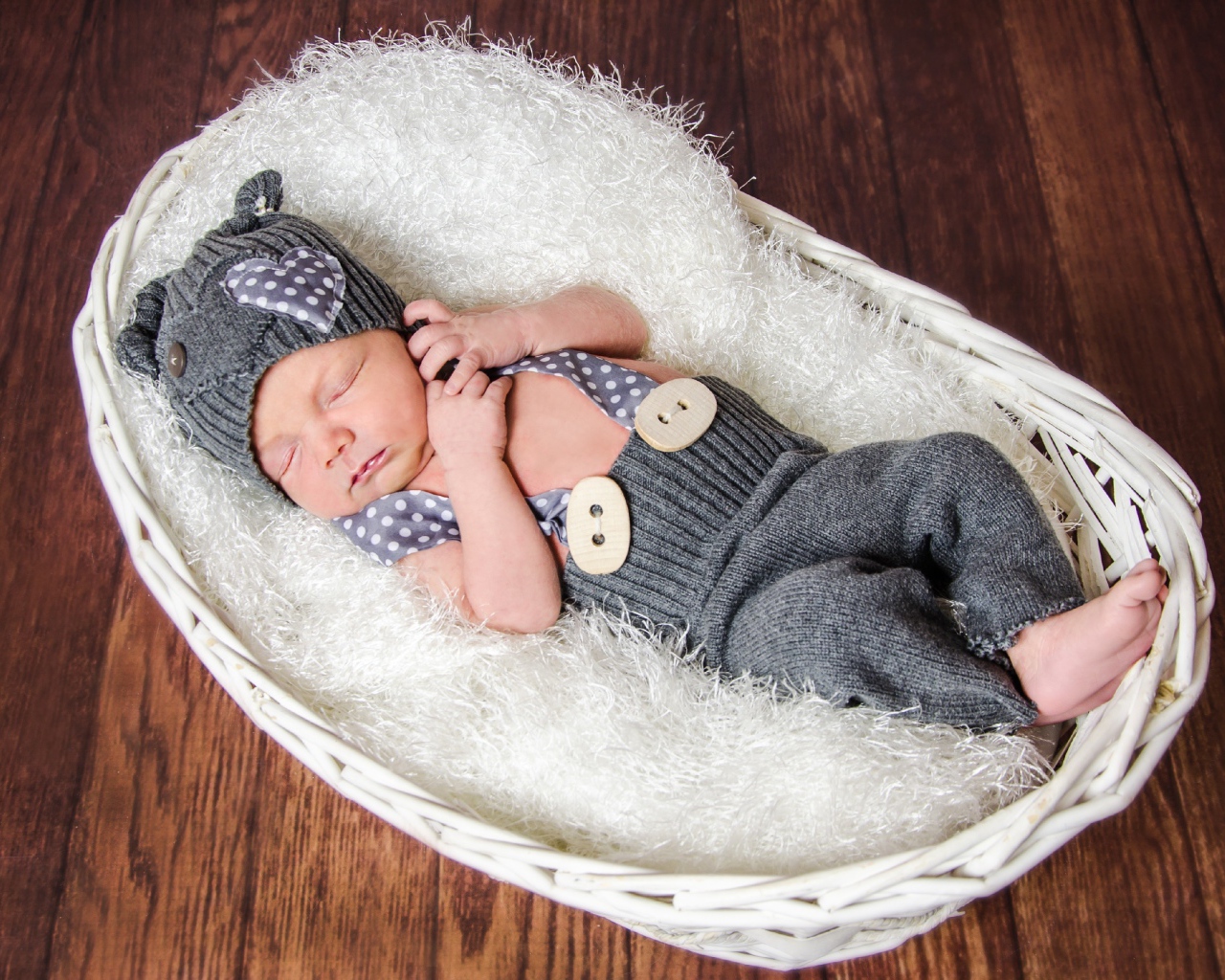 Спящий младенец в сером костюме в белой корзине