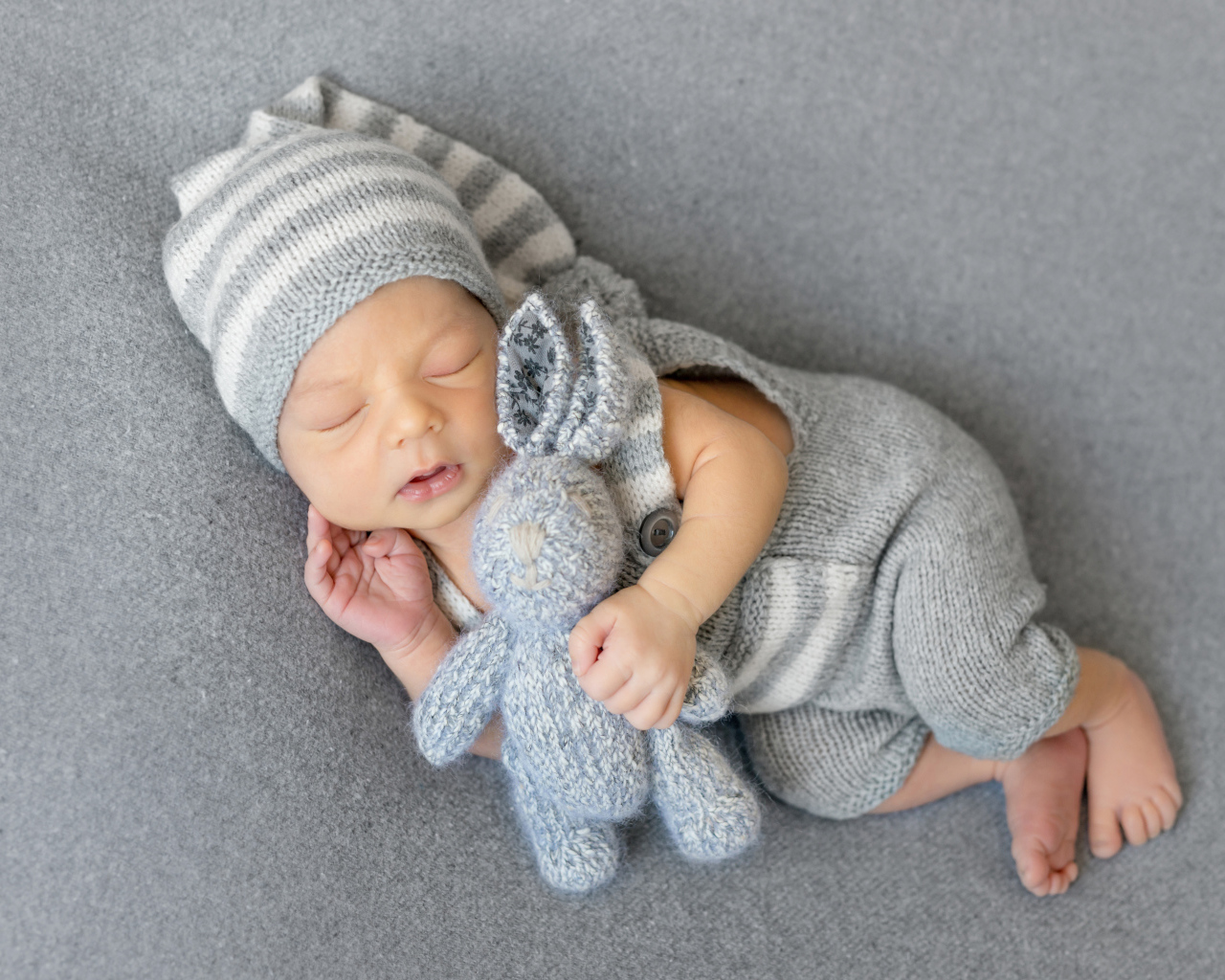 Спящий младенец с серым вязаным зайцем
