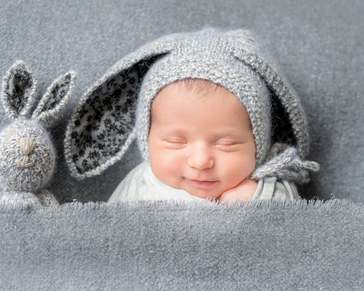 Маленький грудной ребенок в серой шапке с ушками