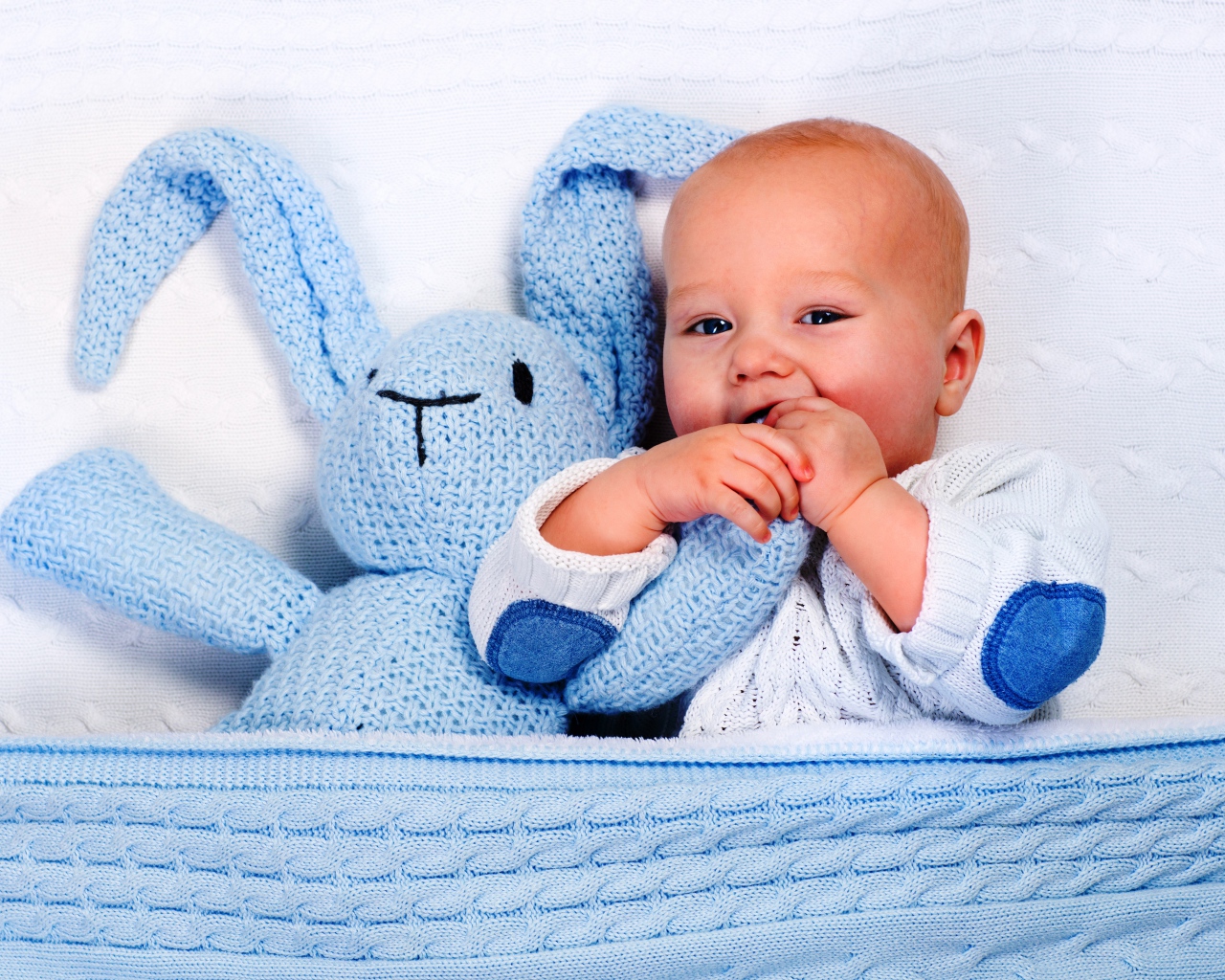 Маленький грудной ребенок грызет мягкую игрушку 