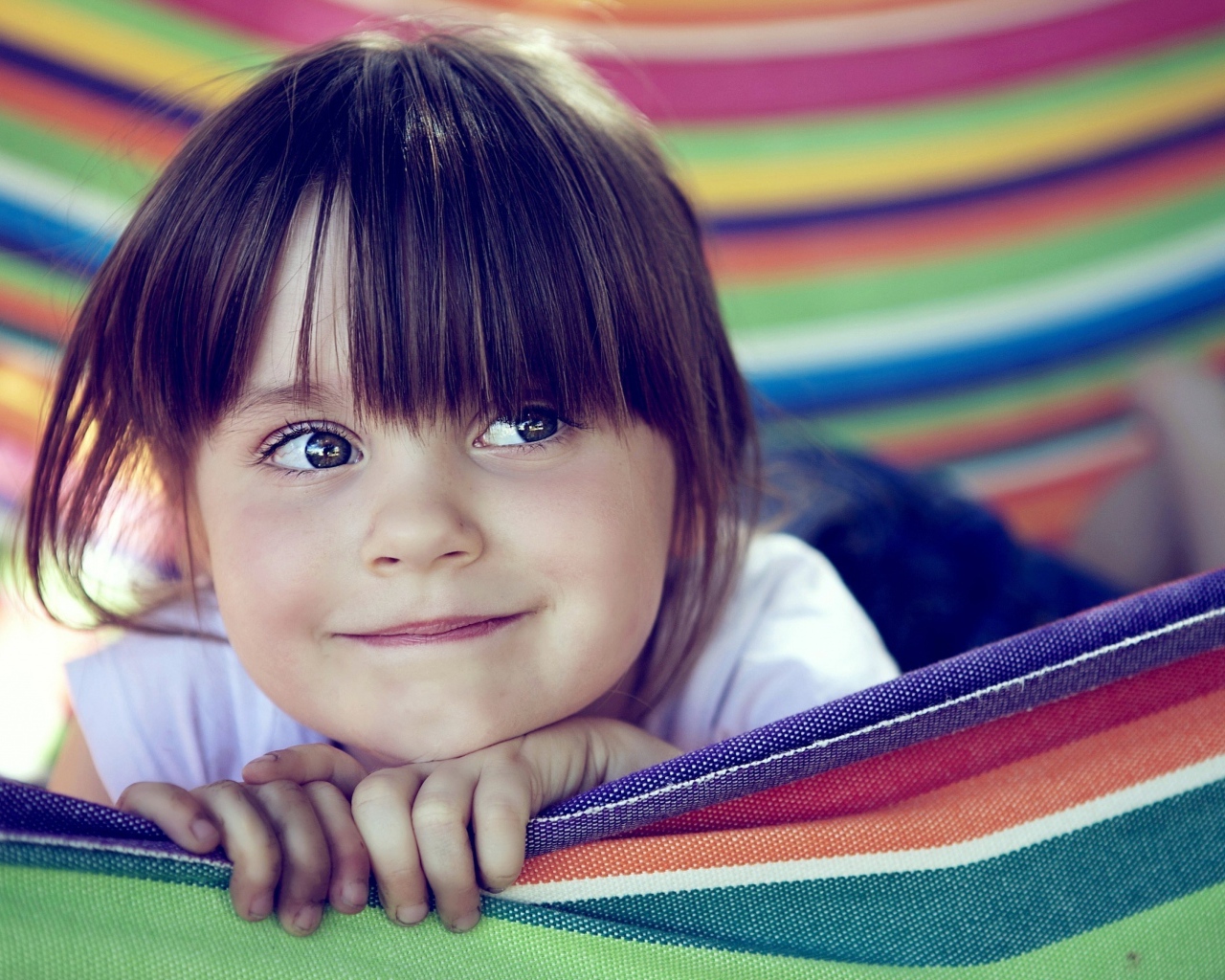 Маленькая кареглазая девочка лежит в гамаке