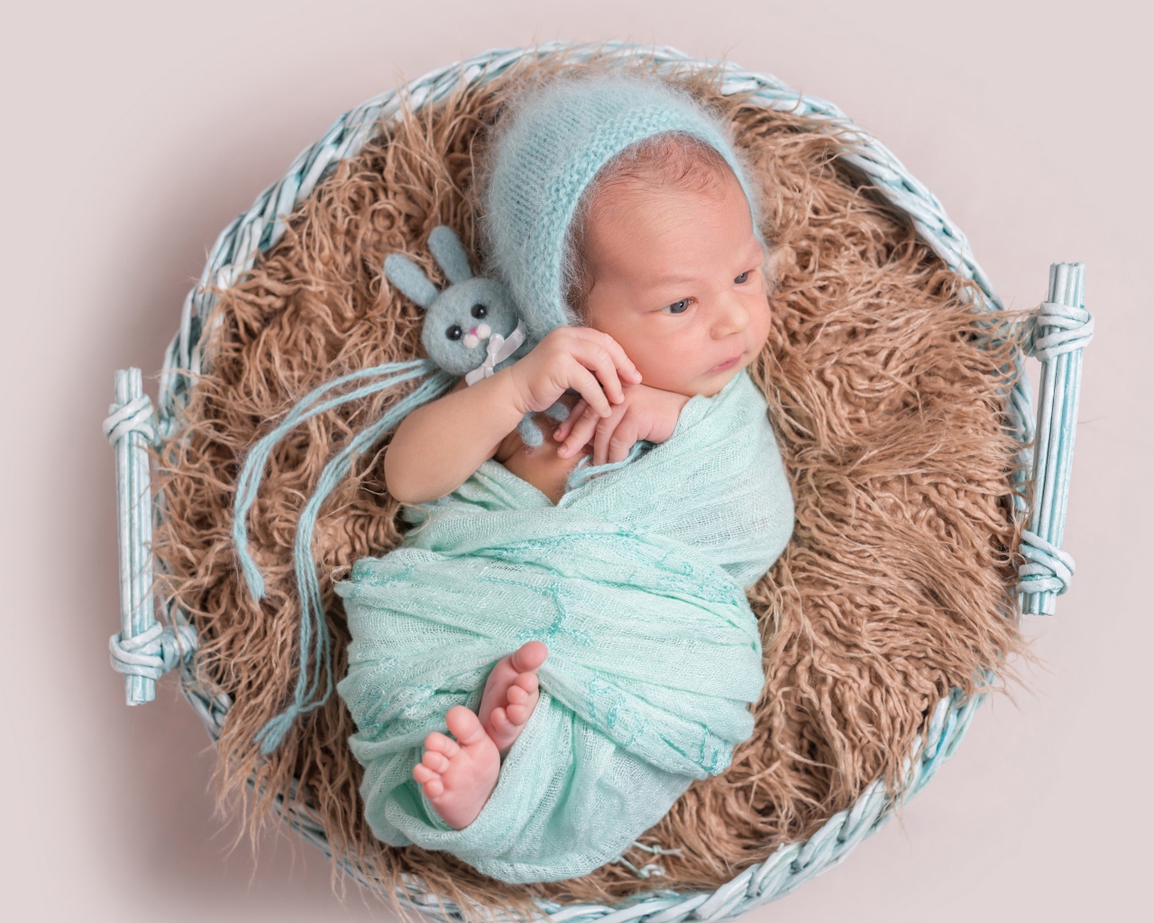 Маленький ребенок в корзине на сером фоне