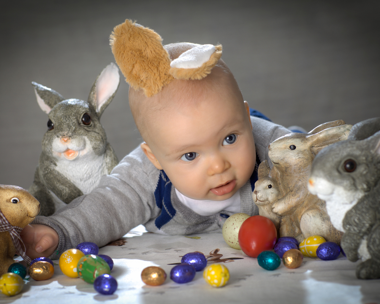 Маленький ребенок с пасхальными кроликами и яйцами