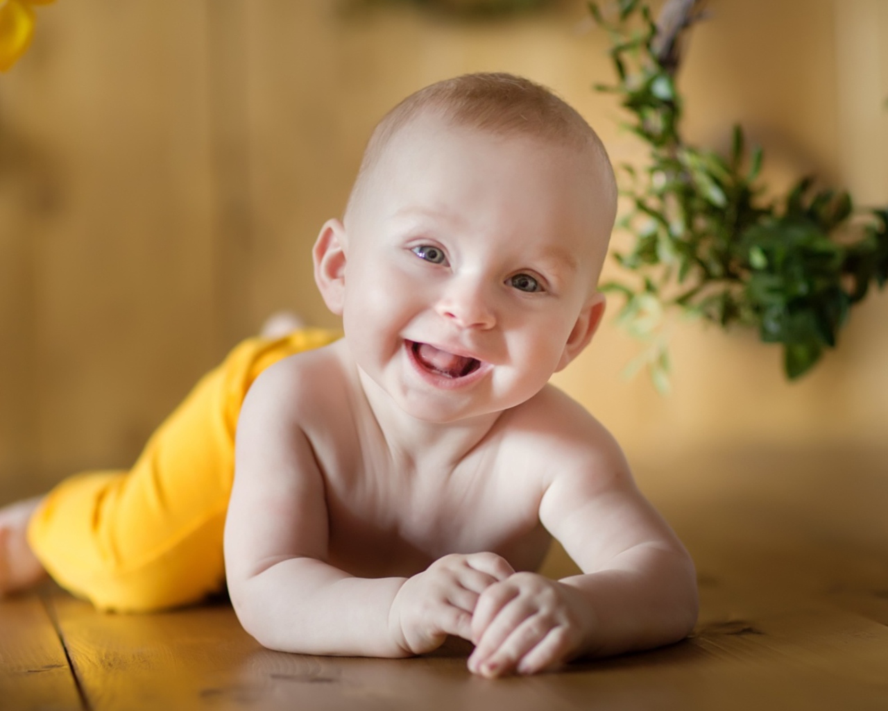 Улыбающийся малыш лежит на деревянном полу