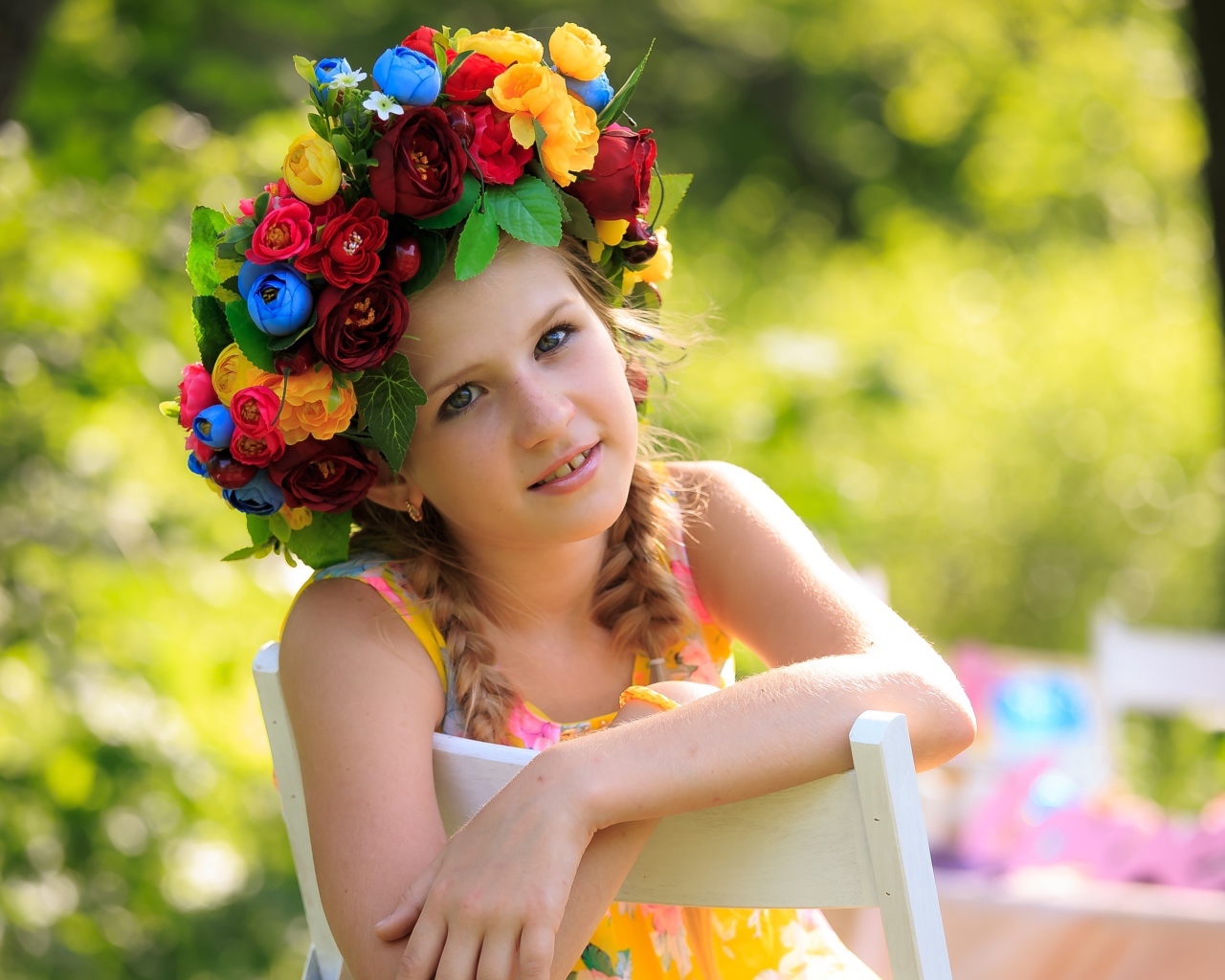 Красивая девочка с венком на голове сидит на стуле