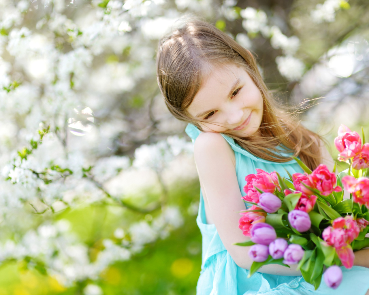 Красивая маленькая девочка с букетом тюльпанов весной