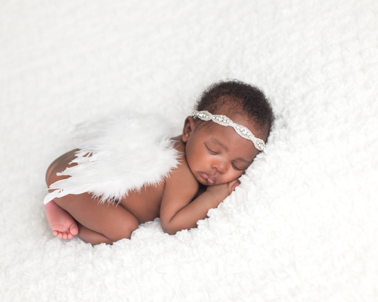 Темнокожий младенец спит с крыльями ангела