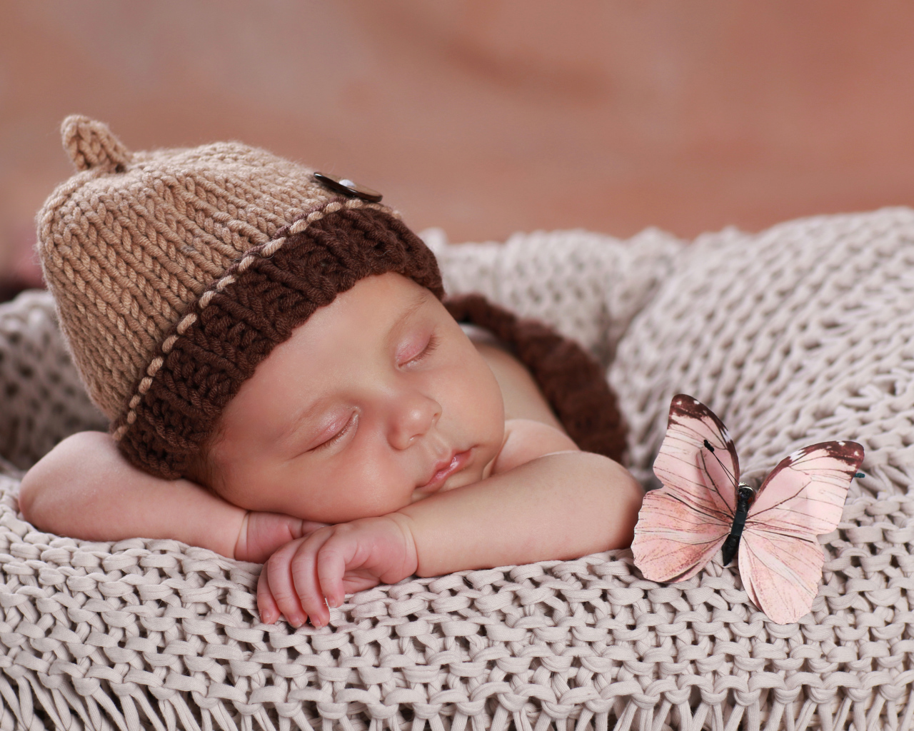 Милый спящий ребенок в коричневой вязаной шапке 