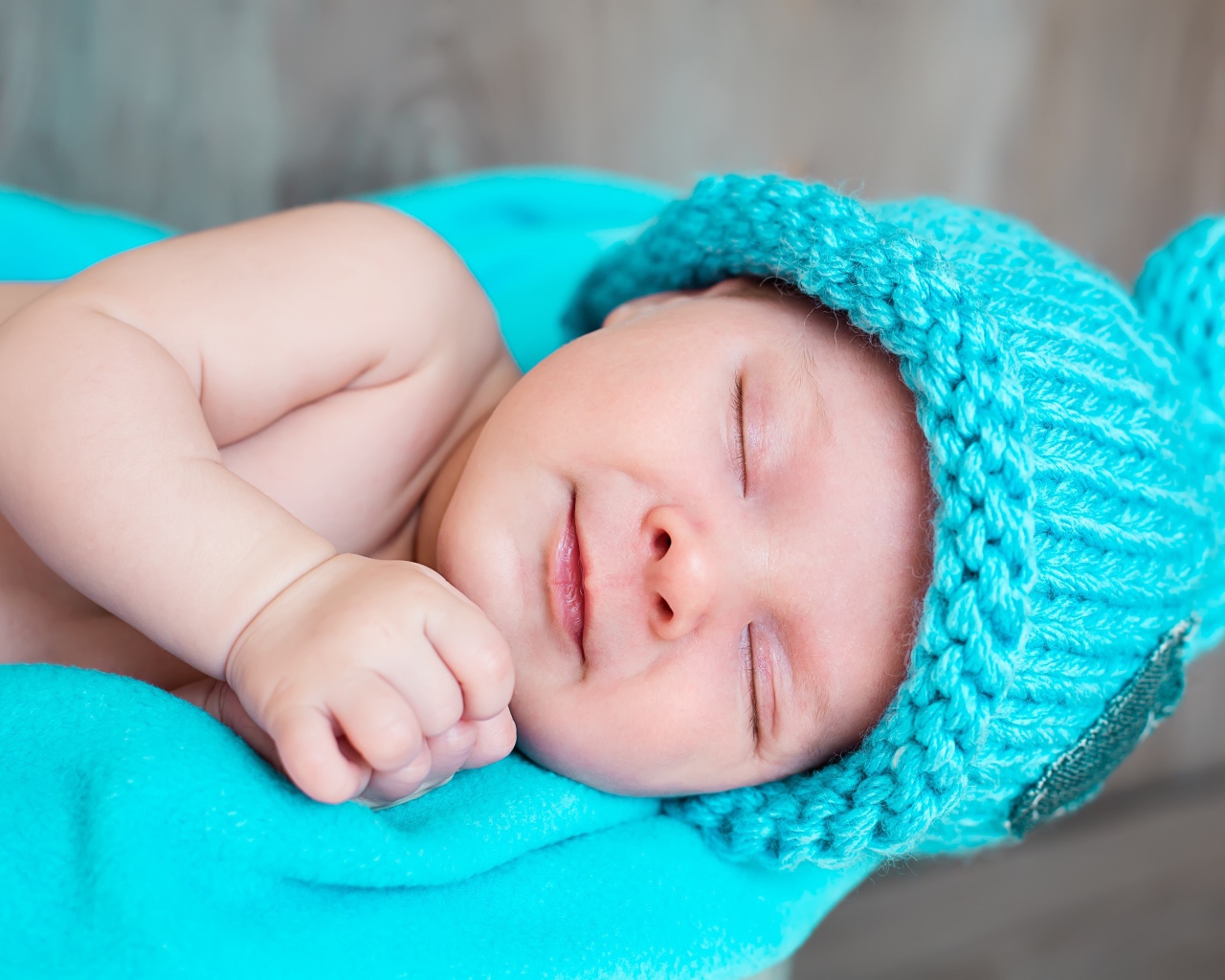 Милый спящий ребенок в голубой вязаной шапке