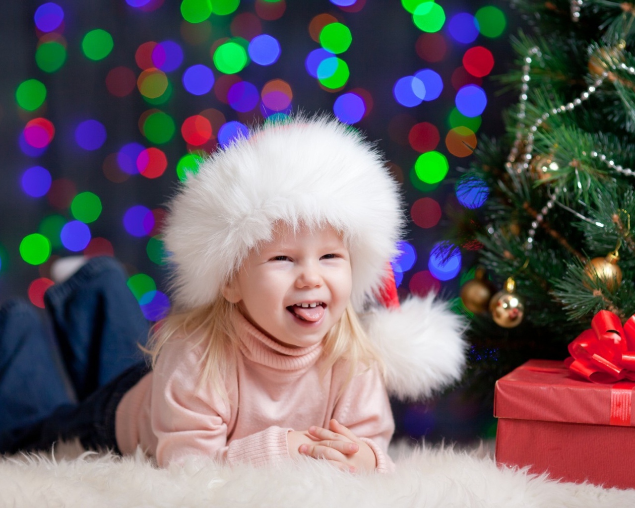 Смешная девочка в новогодней шапке у елки