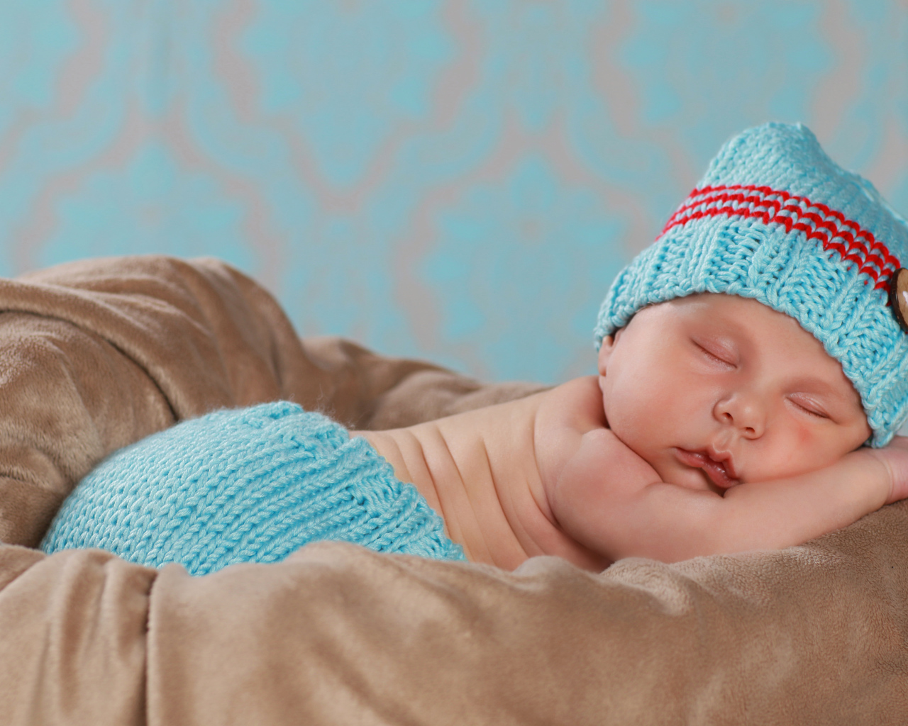 Забавный спящий младенец в голубом вязаном костюме 
