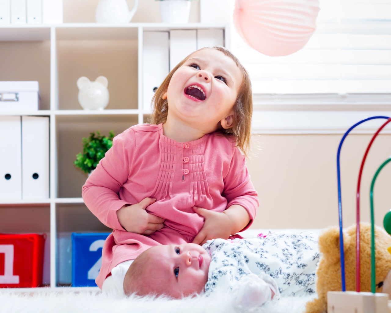 Смеющаяся маленькая девочка с младенцем