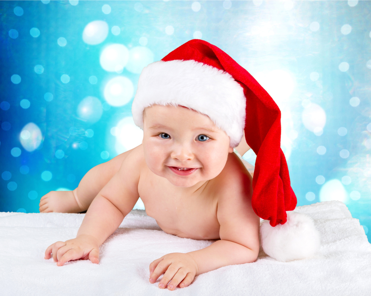Маленький голубоглазый ребенок в красном новогоднем колпаке
