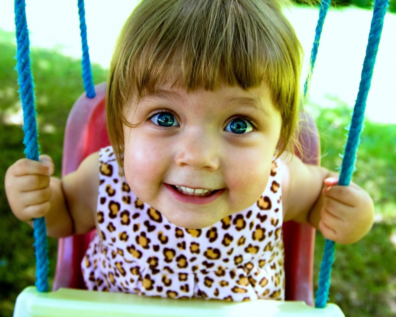 Маленькая голубоглазая девочка на качели
