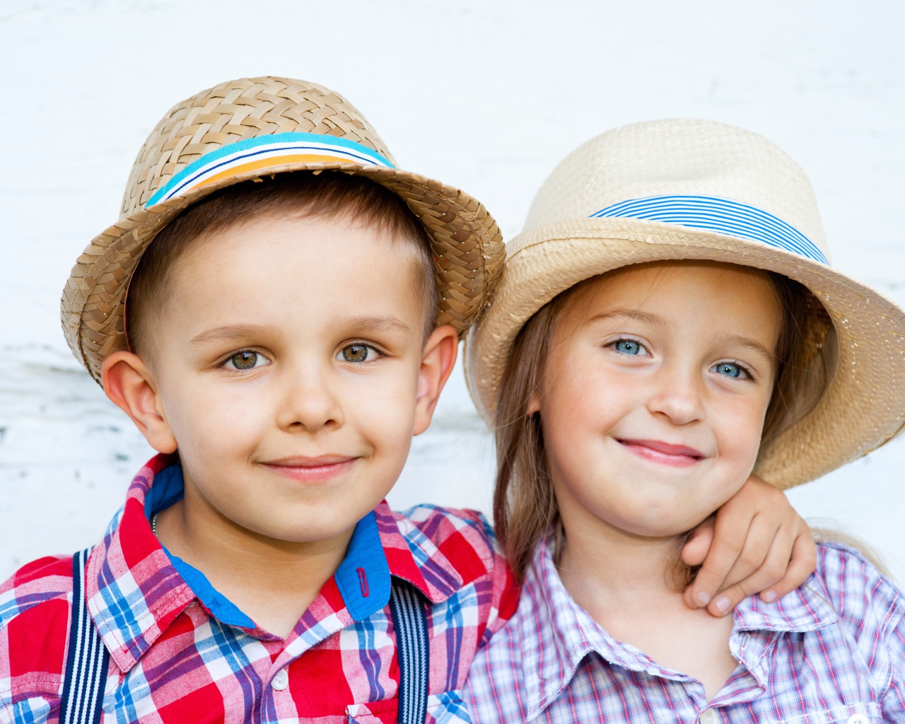 Маленькие мальчик и девочка в соломенных шляпах на пляже