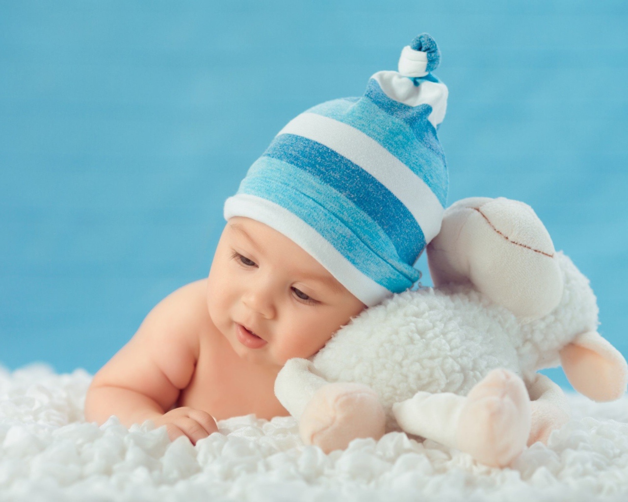 Маленький мальчик в голубой шапке с игрушкой 