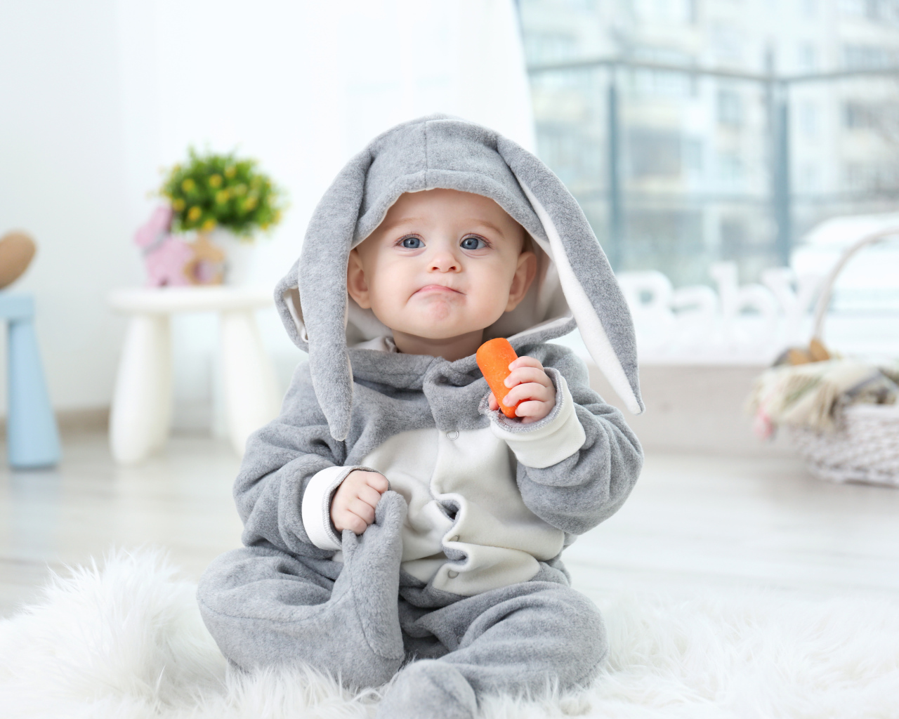 Маленький мальчик в костюме зайчика с морковкой в руке