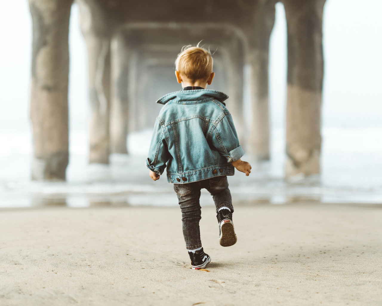 Маленький мальчик в джинсовой куртке спиной